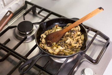 Fried mushrooms in a pan, cooked by a woman.