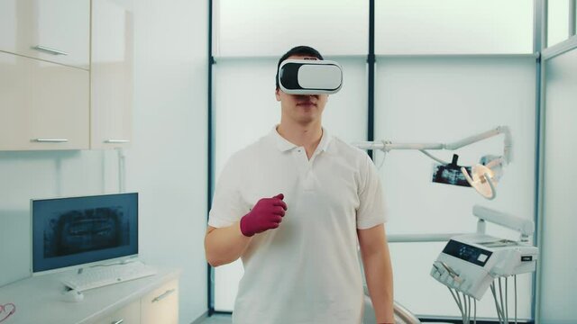 Close-up of multiracial doctor in virtual reality glasses speaking something and gesturing in modern sports lab.