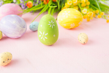 Easter eggs with wild flowers on a wooden pink table background