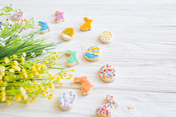Easter cookies, bunnies and eggs with flowers on white wooden table