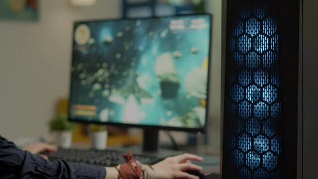 Close up of gamer using professional RGB mouse and keypad playing space shooter tournament in gaming home studio. Pro player streaming online video game during virtual championship on powerful