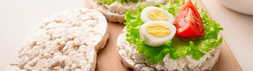 Close up rice cakes with cream cheese and quail eggs with lettuce and tomato banner