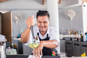 Bartender is making cocktail at counter bar.