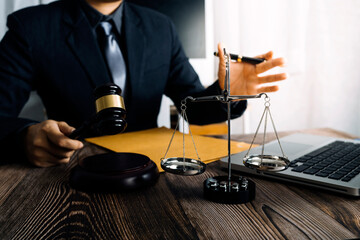Justice and law concept.Male judge in a courtroom with the gavel, working with, computer and docking keyboard, eyeglasses, on table in morning light