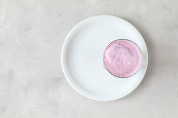 White round plate and round glass with a cocktail of milk and blueberries with foam - the concept of two circles and their combination - top view