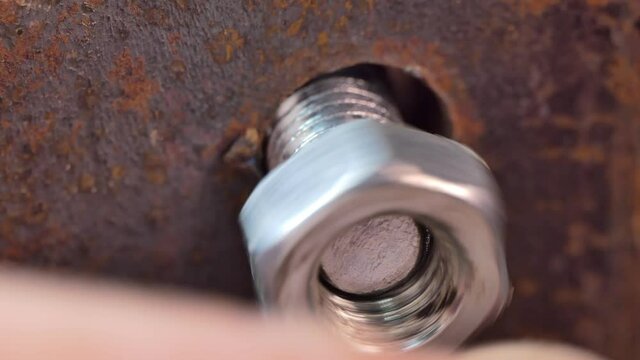 Workshop.Macro. The master inserts the bolt into the hole and tightens the nut.