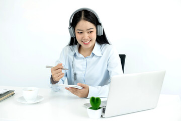 Video call, a young Asian woman wearing headphones, communicates via online video long distance, looking at the digital laptop screen, happily greeted with a friend