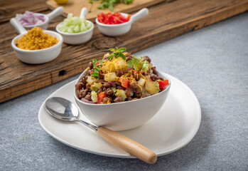 black gram or kala chana chaat with boiled potato, onion, tomato with a dash of lemon juice served on a white bowl