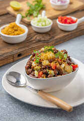 black gram or kala chana chaat with boiled potato, onion, tomato with a dash of lemon juice served on a white bowl