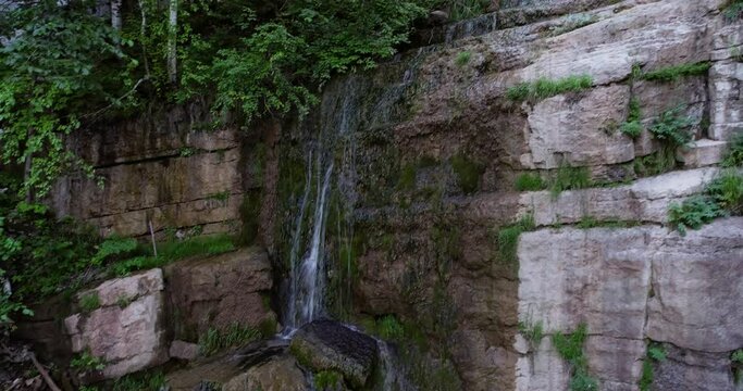 Mountain creek with cascade waterfall and rocky arch in wild nature reserve in Ural Mountains. Aerial drone wide shot at summer day.