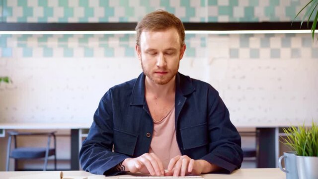 Young casual man typing on computer keyboard, satisfied with the result