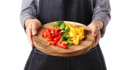 Chef holding chopped bell pepper in wooden cutting board