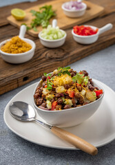 black gram or kala chana chaat with boiled potato, onion, tomato with a dash of lemon juice served on a white bowl