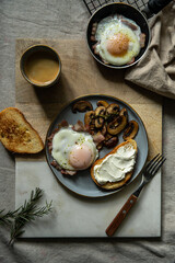 Breakfast with fried egg(sunny side up) with bacon, grilled with rosemary mushrooms and toast with cream cheese. 