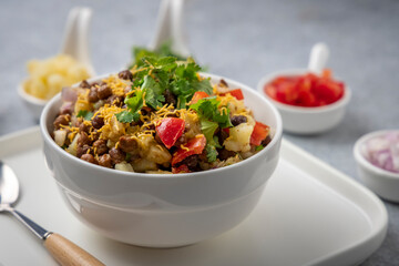 black gram or kala chana chaat with boiled potato, onion, tomato with a dash of lemon juice served on a white bowl