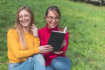 Two women enjoying reading a book in a park