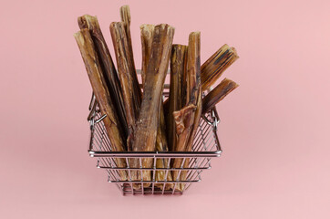 Shopping basket with dog treats on a pink background.