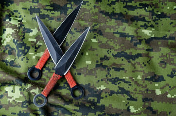 Black Throwing knives on camouflage cloth.