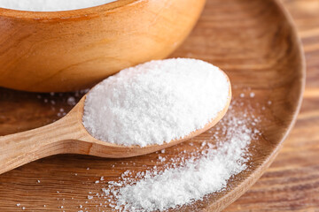 Spoon of salt on wooden background