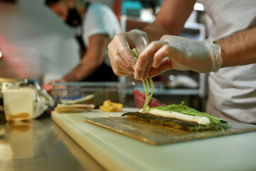 Chef in the kitchen prepares delicious sushi