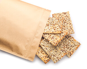 Tasty crackers with seeds in bag on white background