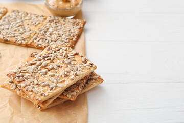 Tasty crackers with seeds on light wooden background