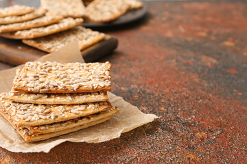 Tasty crackers with seeds on grunge background
