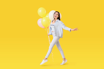 Fototapeta na wymiar Beautiful young woman with balloons on color background