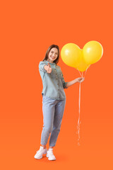 Beautiful young woman with balloons showing thumb-up on color background