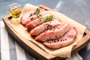 Board with fresh raw meat and spices on color background