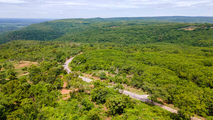 Obraz premium Aerial view from drone going through road on the mountain with green forest. View from the drone of the curve road. 