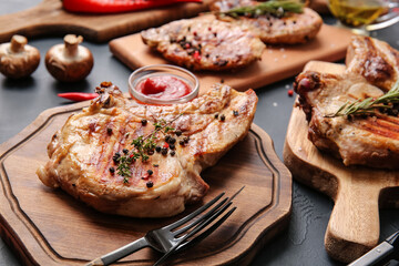 Boards with tasty steaks and spices on dark background