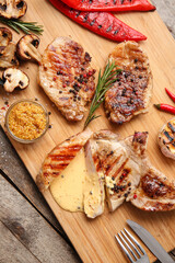 Board of tasty steaks with spices and sauce on wooden background
