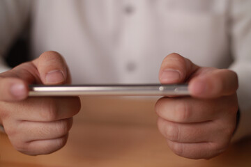 Close up of adult person hands holding and using smart phone to play online game. Leisure activity