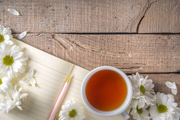 Chamomile flowers, notebook and tea background