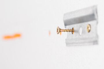 metal fasteners for kitchen furniture fixed on a concrete wall, close-up