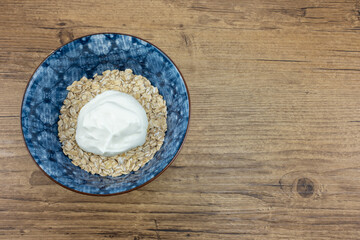 In a blue bowl on a wooden background are oatmeal with Greek yogurt
