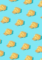 Creative pattern made of freshly baked croissant on pastel blue. Minimal homemade pastry background.