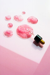 Pink cosmetic drops with pipette on bright backdrop. Skincare product closeup. Beauty banner vertical concept