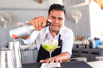 Bartender is making cocktail at counter bar.
