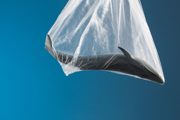 Ocean pollution concept, toy whales in plastic bag on blue background