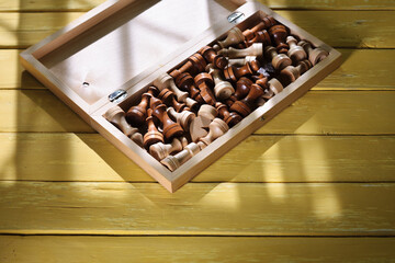 wooden chess in folding chessboard, yellow vintage table