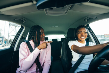 Young pretty african girlfriends having fun driving in the city traffic