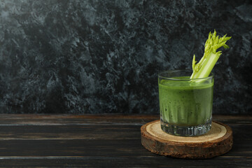 Glass of green smoothie with сelery on board on wooden table