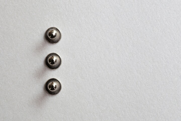 minimalism close-up three grommet, rivet, snap, button on the paper silver background.