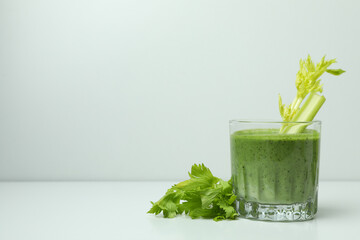 Glass of green smoothie with сelery on white table