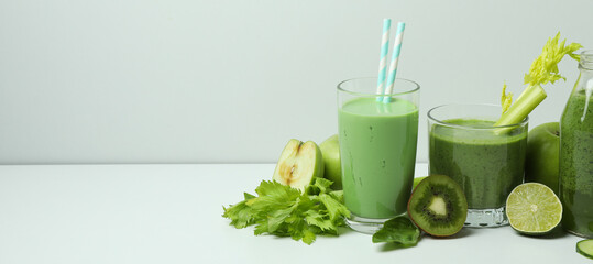 Glasses of green smoothie and ingredients on white table