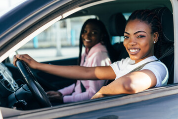 Two african female friends on road trip driving in the car
