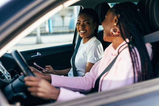 Two beautiful and pretty african women driving in car of their dream. Two women smiling because of successful purchase of automobile in car dealership.