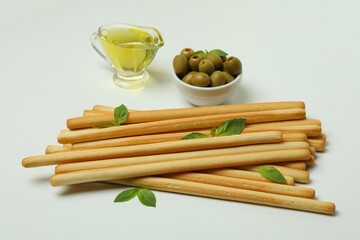 Grissini with basil, olives and oil on white background